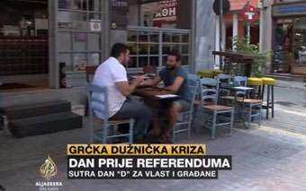 Two men sit at a table outside a café on a quiet street as an Al Jazeera news caption in Bosnian covers the Greek Referendum and debt crisis. Empty chairs and tables surround them, emphasizing the subdued atmosphere.