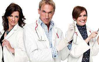 Three people in white lab coats and stethoscopes stand side by side, smiling confidently. The scene evokes a CH4 Embarrassing Bodies vibe as the person in the middle puts on medical gloves, while the others hold medical instruments against a white background.