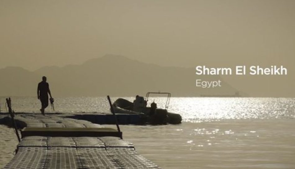 A person walks on a floating dock over calm water at sunset, with boats nearby and mountains in the background. Text reads “Sharm El Sheikh, Egypt,” highlighting the beauty of Egypt tourism.