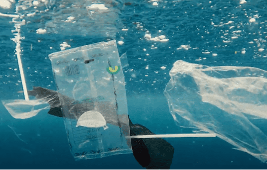 Plastic bags and other debris float in blue ocean water, highlighting marine pollution and the urgent need for EU plastic waste reduction to protect the environment.
