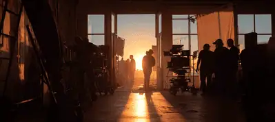 People stand in a large, open room filled with film equipment as the sun sets outside, casting warm light and long shadows—a perfect scene for filming in the Canary Islands.