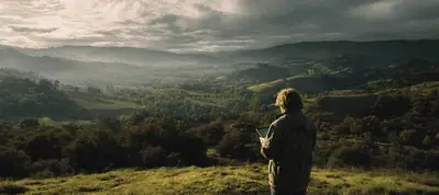 A person stands on a hill overlooking a vast, green valley with rolling hills, trees, and dramatic clouds in the sky, holding a notebook or tablet—capturing the beauty as if filming in Norway.
