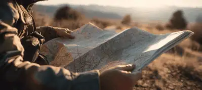 A person sitting outdoors in a natural landscape studies a large paper map, with blurred hills and soft sunlight in the background—an ideal scene for filming in Israel.