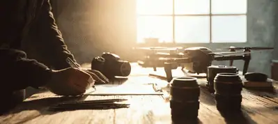 A person writes on paper at a wooden table with a camera, camera lenses, and a drone—essential gear for filming in Norway—illuminated by sunlight streaming through a window in the background.