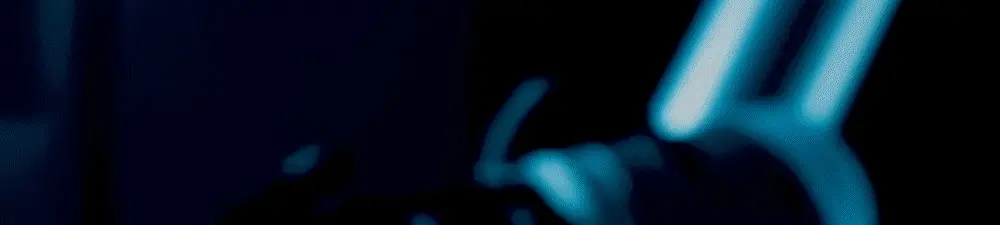 A close-up of a blue lightsaber igniting in the dark during filming in Saudi Arabia, with the blade glowing brightly and casting blue light on the surroundings.