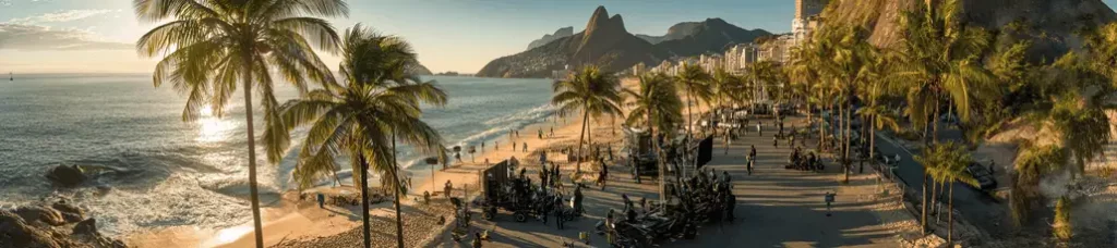 A panoramic view of a sunny beach with palm trees, people relaxing, waves hitting the shore, and mountains in the background—perfect for filming in Rio de Janeiro along the vibrant city coastline.