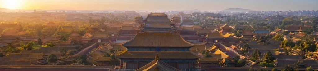 Golden tiled roofs of an imperial palace complex in Beijing at dawn.