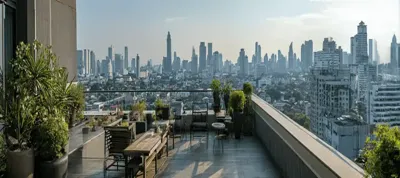 A rooftop terrace with tables, chairs, and potted plants overlooks a city skyline with numerous modern high-rise buildings under a partly cloudy sky—an ideal setting for filming in Vietnam.